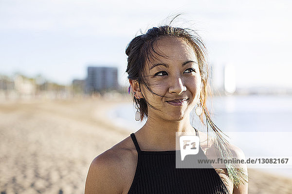 Nachdenklich-sportliche Frau im Sommer am Strand