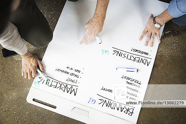Ausgeschnittenes Bild von Geschäftsleuten  die in einem kreativen Büro an einer weißen Tafel schreiben