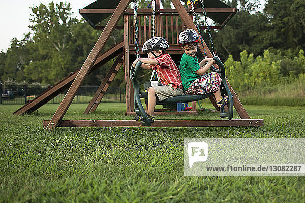 Playful brothers swinging in playground