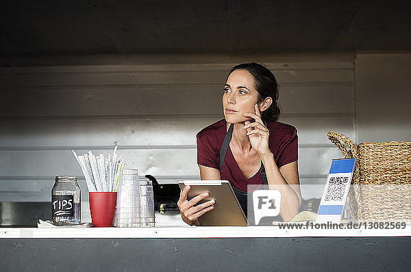 Thoughtful female vendor with tablet computer in food truck