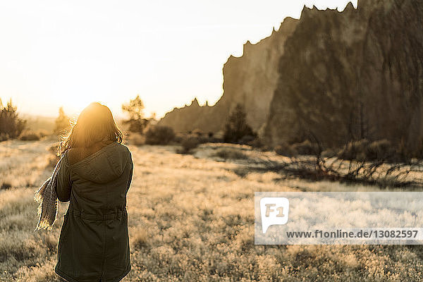 Rear view of woman standing on field at Smith Rock State Park against clear sky