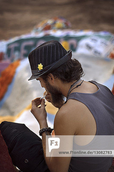 High angle view of man holding weed while sitting at Salvation Mountain