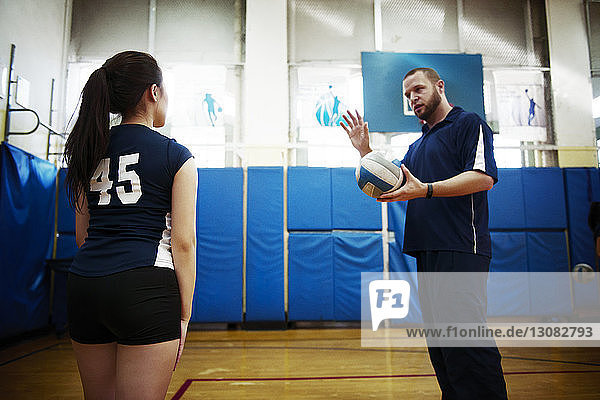 Männlicher Trainer erklärt Teenagermädchen auf Volleyballfeld