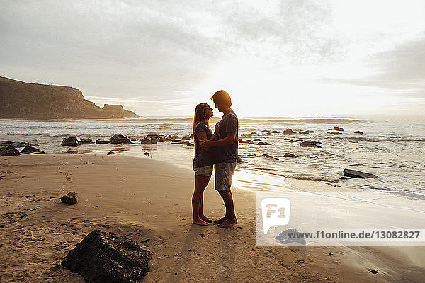 Seitenansicht eines romantischen Paares  das sich am Strand gegenübersteht