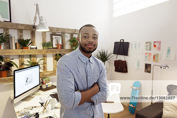 Portrait of confident male illustrator standing arms crossed in creative office