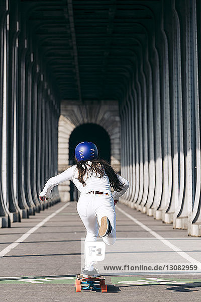 Rückansicht einer Frau beim Skateboarden unter der Brücke