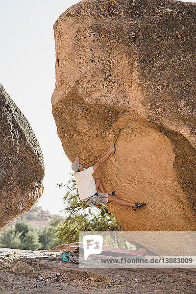 Ein Mann in voller Länge klettert am Fels in der Wüste