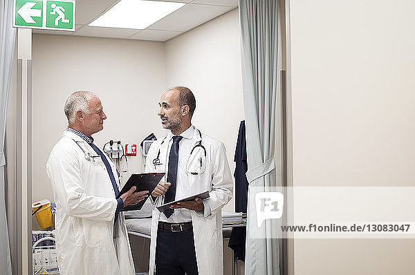 Doctors discussing medical reports while standing in medical examination room
