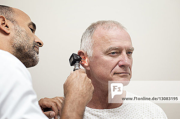Arzt benutzt Otoskop bei der Untersuchung des Patientenohrs im Krankenhaus