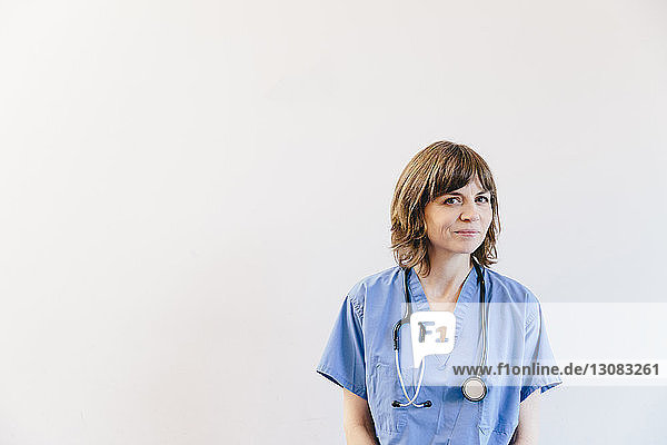 Porträt einer Ärztin mit Stethoskop vor weissem Hintergrund stehend