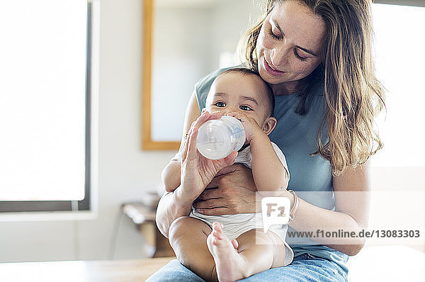 Mutter füttert Säugling  während sie zu Hause am Tisch sitzt