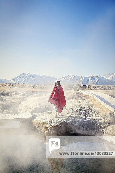 In eine Decke gehüllte Frau steht auf einem Felsen in den Mammoth Lake Hot Springs