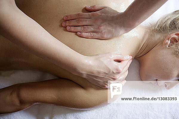 Overhead view of relaxed woman receiving back massage from therapist in spa