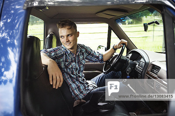 Happy man looking away while sitting in pick-up truck