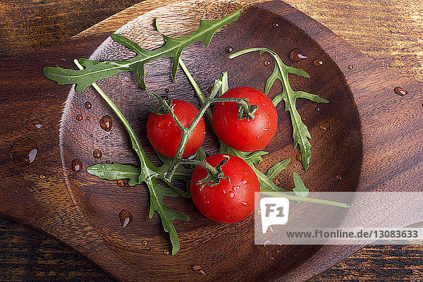 Draufsicht auf nasse Tomaten und Rucola auf Holztisch