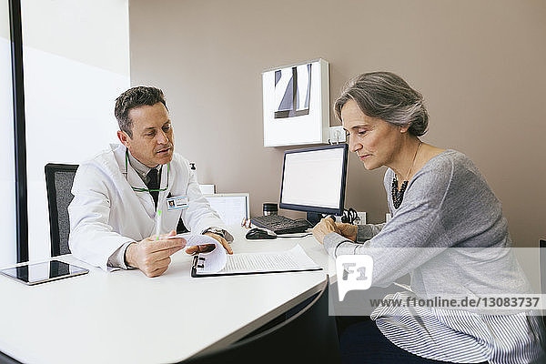 Doctor discussing with patient while sitting against wall at hospital