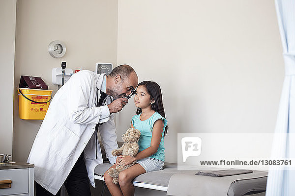 Arzt verwendet Otoskop zur Untersuchung des Ohrs eines Mädchens im medizinischen Untersuchungsraum