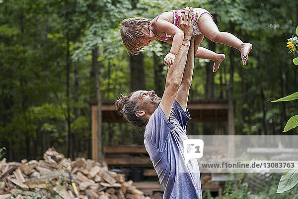 Happy father lifting daughter in backyard