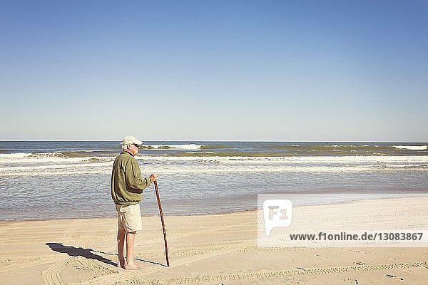 Seitenansicht eines älteren Mannes  der am Strand am Ufer steht