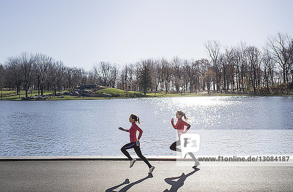 Two women running by pond