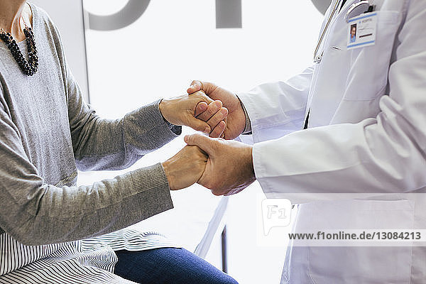 Nahaufnahme eines Arztes  der die Hände hält  während er einen älteren Patienten tröstet