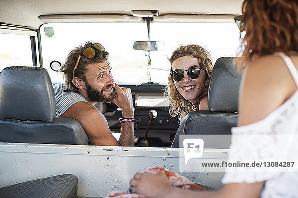 Happy friends talking in off-road vehicle