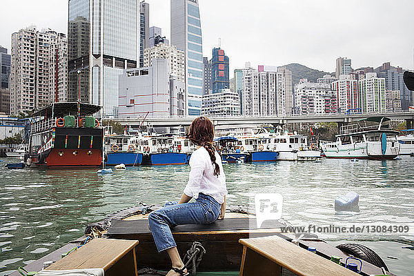 Seitenansicht einer Touristin  die im Boot sitzend auf Gebäude schaut