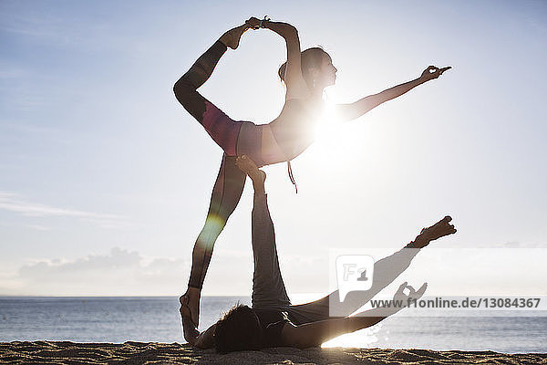 Ein Paar macht im Sommer Yoga am Strand gegen den Himmel