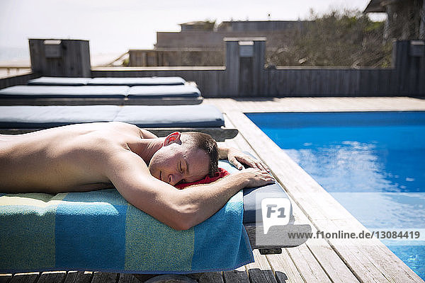 Seitenansicht eines hemdlosen schwulen Mannes  der sich auf einem Liegestuhl am Pool entspannt