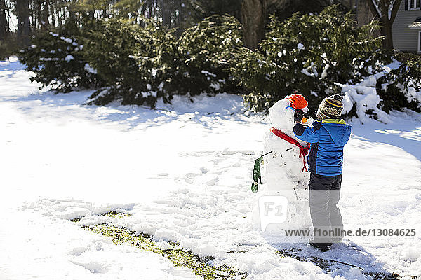 Boy making snowman on snowy field