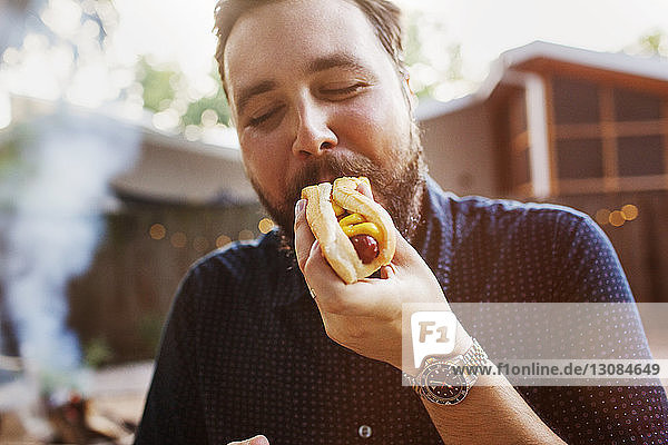 Mann isst Hot Dog im Hof