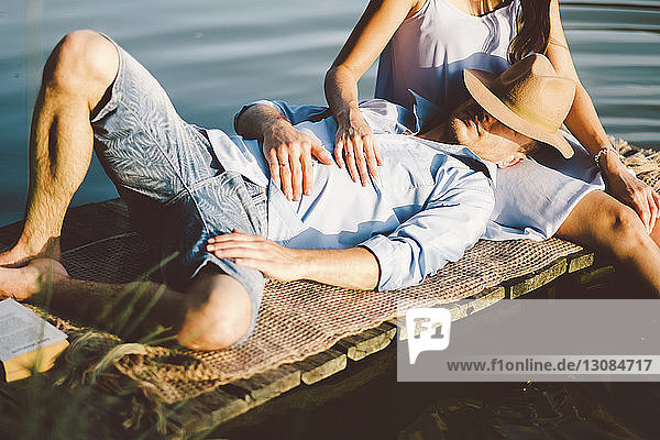 Mitschnitt der Freundin mit auf dem Schoß liegendem Freund am See im Park sitzend