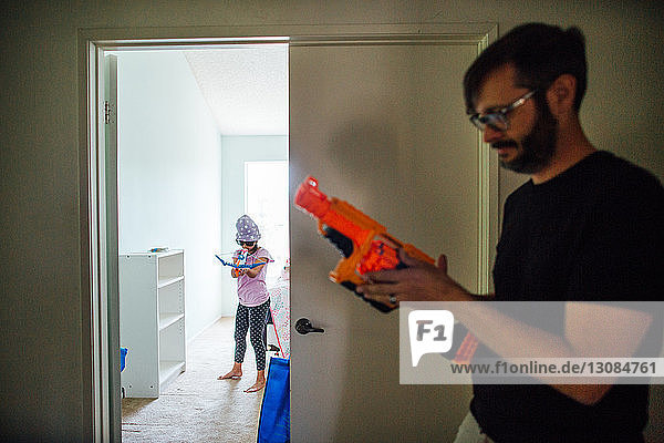 Vater und Tochter spielen mit Spielzeugpistolen vor der Tür