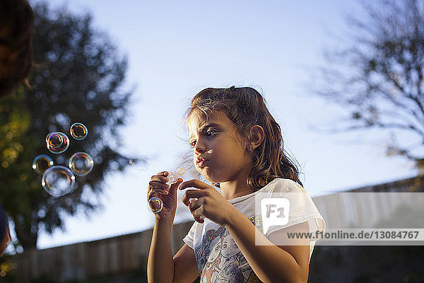 Low angle view of girl making bubbles against sky