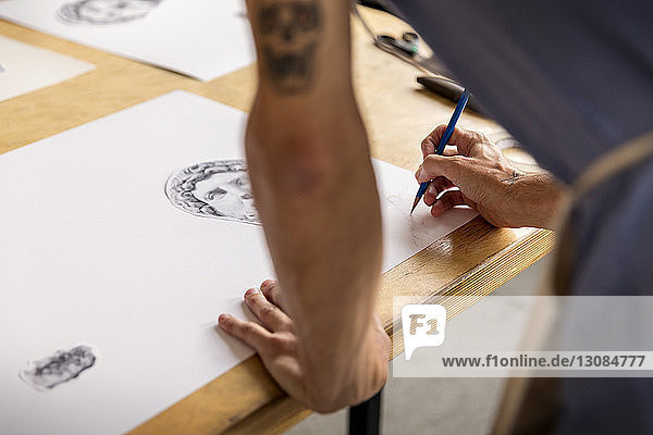 Beschnittenes Bild eines Mannes  der eine Skizze zeichnet  während er in der Werkstatt steht