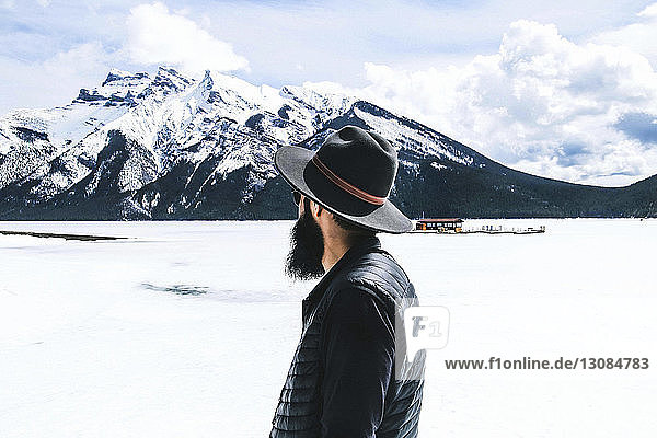 Rear view of man in fedora hat looking at view against cloudy sky