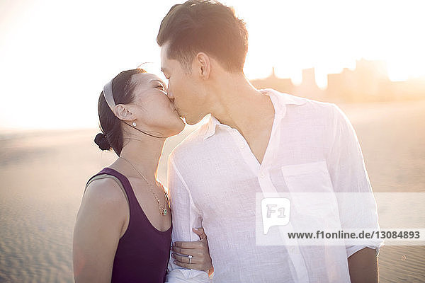 Zärtliches Paar küsst sich am Strand stehend