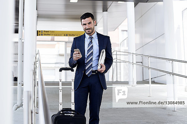 Portrait of confident businessman holding smart phone at subway station