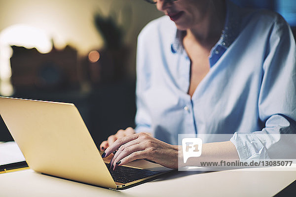 Ein Teil der Geschäftsfrau benutzt einen Laptop  während sie im Heimbüro sitzt