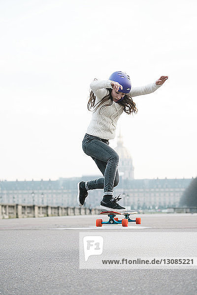 Frau springt in voller Länge beim Skateboardfahren gegen Musee de larmee