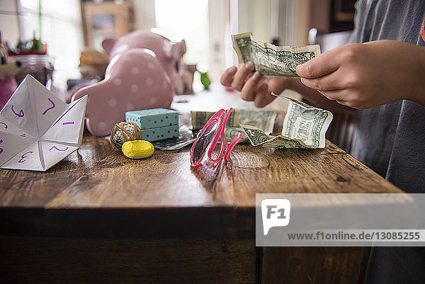 Mittendrin ein Mädchen  das Geld zählt  während es zu Hause an einem Holztisch steht