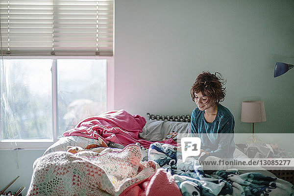 Lächelndes Mädchen spielt Videospiel  während es sich zu Hause im Bett entspannt