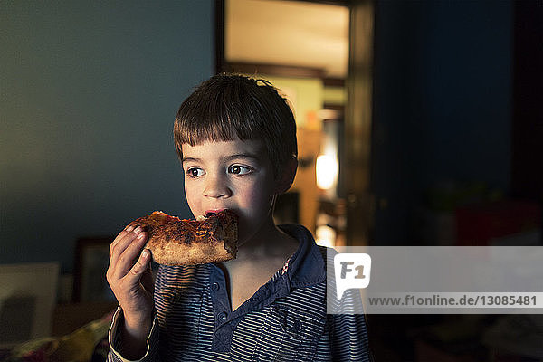Junge isst Brot  während er zu Hause steht