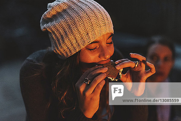 Frau genießt Smore  während sie nachts im Hinterhof sitzt