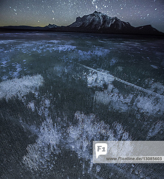Hochwinkelaufnahme von Methanblasen im Abraham-See bei den Bergen während der Nacht