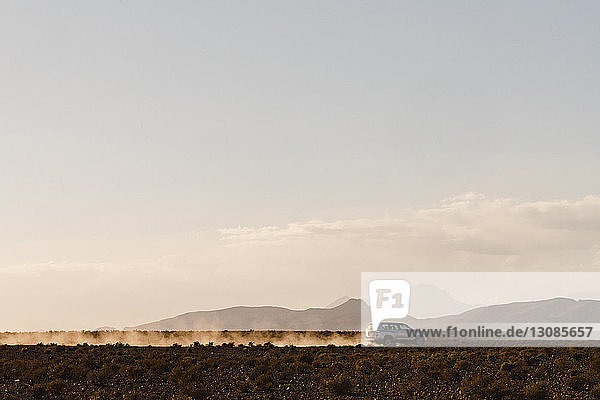 Silhouetten-Geländewagen bewegt sich in der Wüste gegen den Himmel