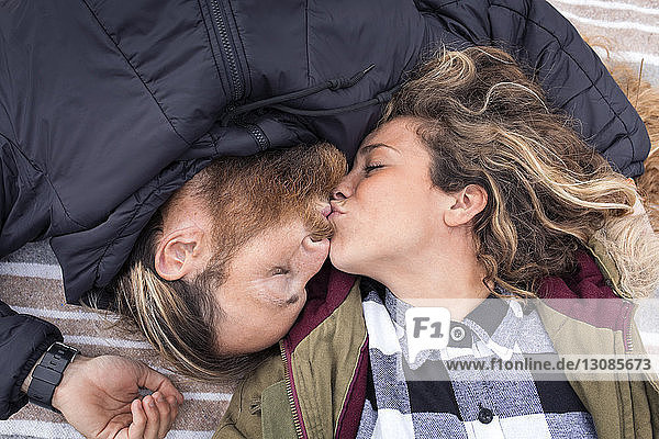 Draufsicht auf ein Paar  das sich küsst  während es auf einer Decke liegt