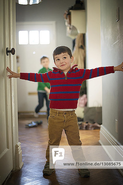 Boy standing with arms outstretched on floor at home