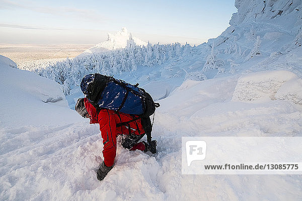 Hochwinkelaufnahme eines Wanderers  der auf einem schneebedeckten Hügel balanciert