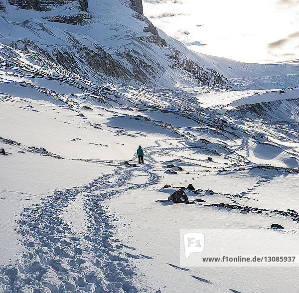 Rear view of hiker standing on snowy field at Icefields Parkway
